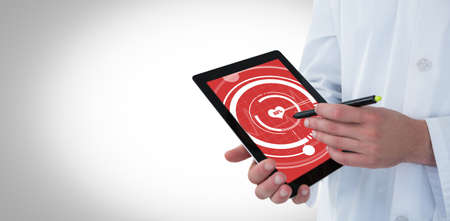 Doctor using digital tablet against digital composite of heart iconの写真素材