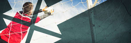 Goalkeeper in red making a save on a clear dayの写真素材