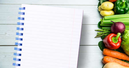 Little Notepad against line of vegetables on table