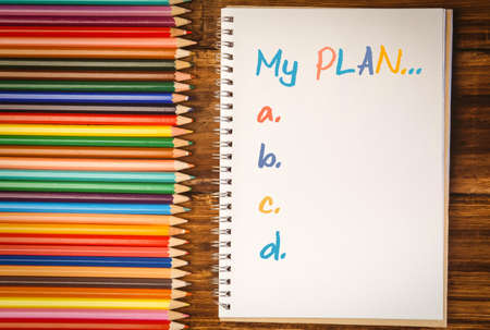 List of plan from a to e  against colour pencils on desk with notepad