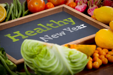 Healthy New Year against wooden tray surrounded with fresh vegetablesの写真素材