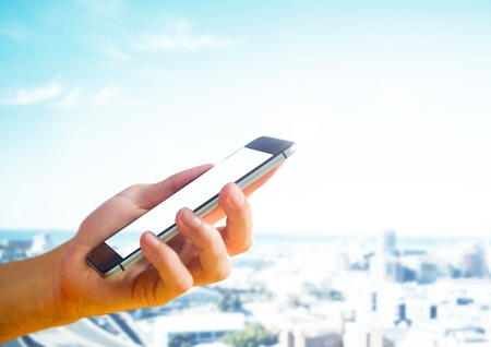 Digital composite of Hand holding phone in cityの写真素材