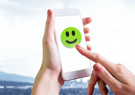 Digital composite of Hand touching smiley face on phone