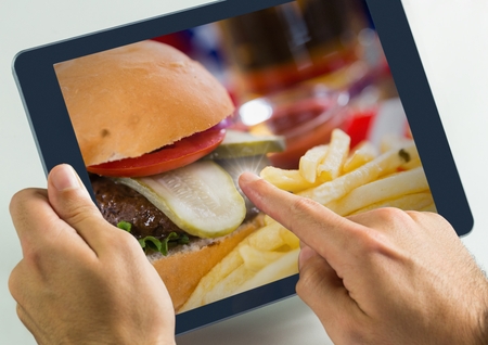 Digital composite of Hand touching tablet with burger food restaurantの写真素材