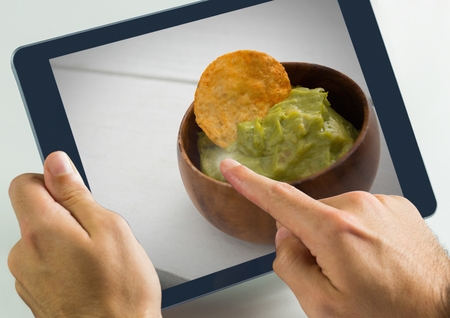 Digital composite of Hand touching tablet with guacamole food restaurant