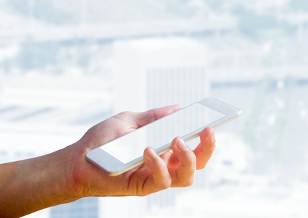 Digital composite of Hand holding phone and cityの写真素材