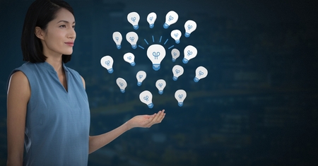 Digital composite of Idea light bulb app icons and Businesswoman with hands palm open and dark backgroundの写真素材