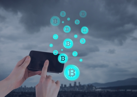 Digital composite of Bitcoin icons and hand holding phone