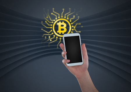Digital composite of Bitcoin icon and hand holding phoneの写真素材