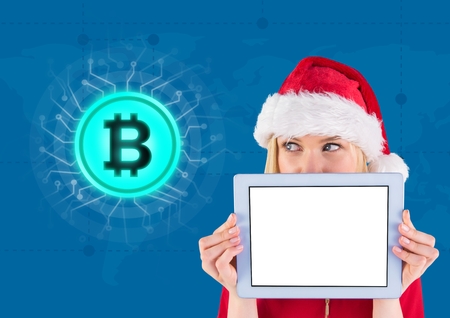Digital composite of Bitcoin icon and female Santa holding tabletの写真素材