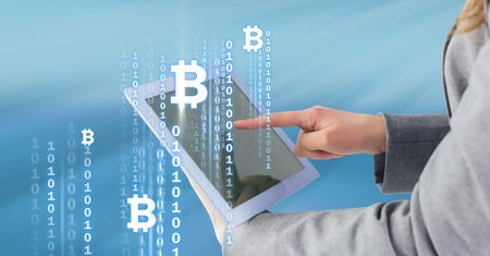Digital composite of Bitcoin icons and interface on tablet in woman's hands