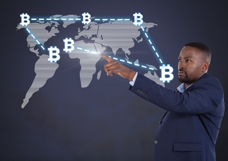 Digital composite of Businessman pointing with bitcoin graphic icons on world mapの写真素材