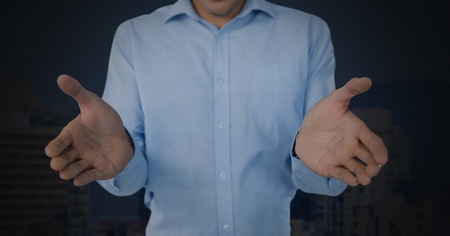 Digital composite of businessman with hands palm open and dark backgroundの写真素材