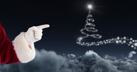 Digital composite of Santa pointing and Snowflake Christmas tree pattern shape glowing in skyの写真素材