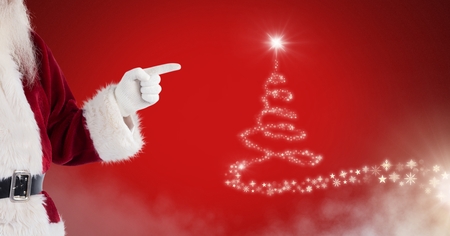 Digital composite of Santa pointing at Snowflake Christmas tree pattern shape glowingの写真素材