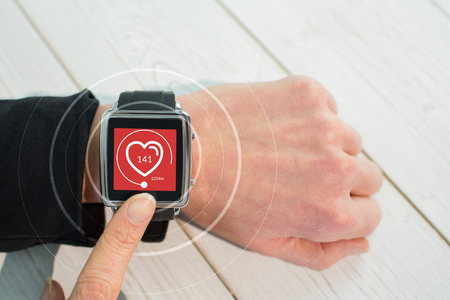 Businesswoman using a smart watch against digital composite of heart iconの写真素材
