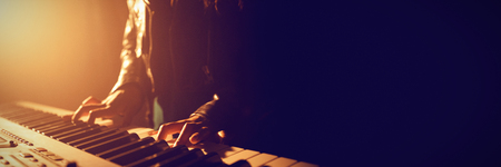 Mid section of female musician playing piano in illuminated nightclubの写真素材