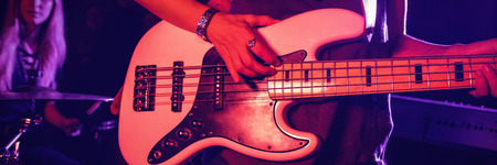 Mid section of female guitarist playing guitar with drummer in nightclubの写真素材
