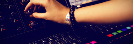 Cropped hand of female audio engineer using sound mixer at recording studio