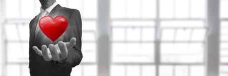 Digital composite of Businessman with open hand and heart in front of windowの写真素材