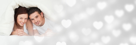Digital composite of Couple under duvet with valentine's love transition heartsの写真素材