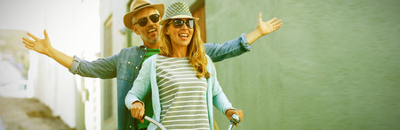 Mature couple enjoying while riding bicycle by buildingの写真素材