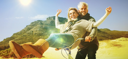 Carefree couple going on a bike ride on the beach on a bright but cool dayの写真素材