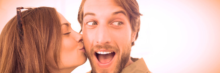 Pretty woman kissing man with beard on cheek against white backgroundの写真素材