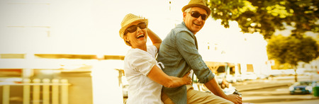 Happy mature couple going for a bike ride in the city on a sunny dayの写真素材