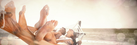 Happy couple napping together in the hammock at the beachの写真素材