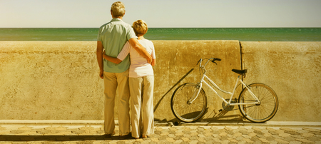 Happy senior couple looking out to the sea on a sunny dayの写真素材