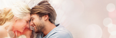 Cute couple relaxing on bed smiling at each other at home in the bedroomの写真素材