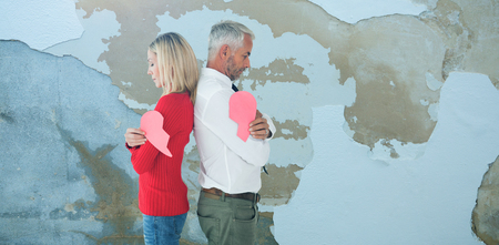 Couple holding two halves of broken heart against rusty weathered wallの写真素材
