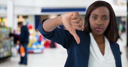 Digital composite of woman in shop with thumbs downの写真素材