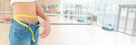 Digital composite of Fit athletic woman in gym measuring waistの写真素材