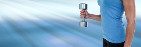 Digital composite of Athletic fit woman lifting weight with shining light backgroundの写真素材