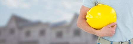 Digital composite of Construction Worker on building site holding helmetの写真素材