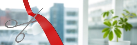 Digital composite of Scissors cutting ribbon with office windows in cityの写真素材
