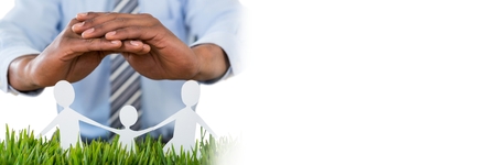 Digital composite of Paper Cut Out family with businessman's hand protectingの写真素材