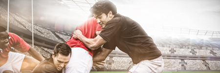 Rugby pitch against rugby players tackling during gameの写真素材