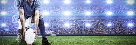 Digital composite image of rugby player positioning ball against digital image of crowded soccer stadiumの写真素材