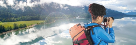 Digital composite of Travelling woman with bag and camera in front of landscapeの写真素材