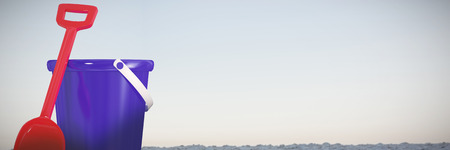 Blue bucket and red shovel against horizon over the sandの写真素材