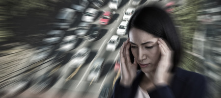 Businesswoman suffering from headache against high angle view of traffic on road