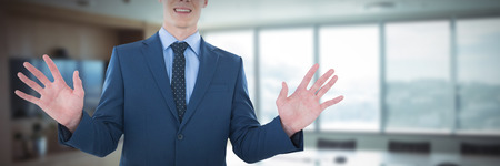 Mid section of smiling businessman using imaginary screen against empty boardroom in officeの写真素材