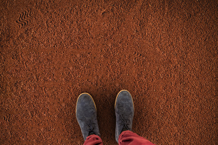 Low section of man wearing shoes against brown earthの写真素材