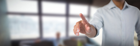 Man pretending to touch an invisible screen against white background against carefree businessman sitting on sofaの写真素材