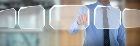 Mid section of smiling businessman using interface while standing with hand in pocket against lift in office buildingの写真素材