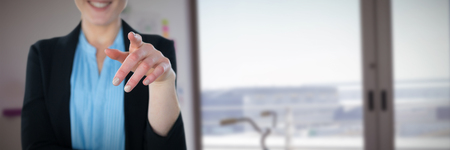 Mid section of smiling businesswoman pointing against interior of creative officeの写真素材