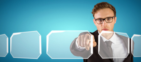 Young serious businessman pointing at camera against abstract blue backgroundの写真素材